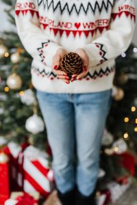 Woman in a white Christmas sweater holds a cone