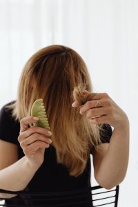 Kaboompics - A woman combs her hair with a jade comb