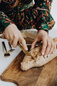 Woman is cutting bread on cutting board