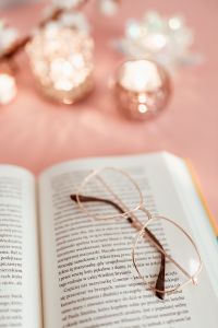 Kaboompics - An open book, candles and glasses on a pink background