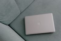 MacBook laptop lying on mint couch