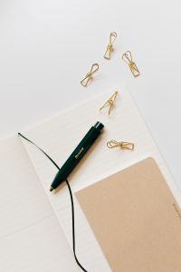 Pen, clips and notebooks on a white desk