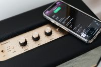Kaboompics - Black speaker on marble table, white wall, mobile phone