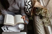 Kaboompics - A woman in a sweater reads a book