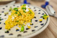 Kaboompics - Yellow rice with greens on a cute plate with blue hearts and a table decorated with flower petals