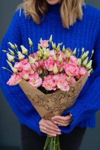 Kaboompics - Close up of woman holding bouquet of pink lisianthus flowers wrapped in brown paper