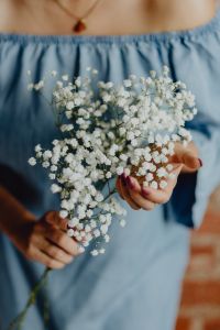 Kaboompics - A woman in a blue dress holds a branch of Baby's Breath flower