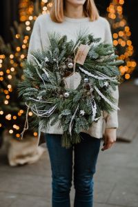 The woman is holding a Christmas wreath in her hands