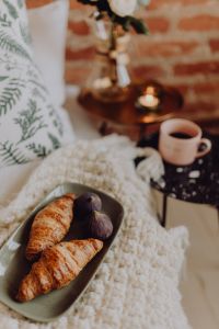 Kaboompics - Croissants and figs on a green plate, a cup of coffee and a candle
