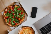 Kaboompics - Top view of the desk with pizza, laptop, phone and hands
