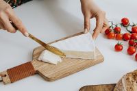 Kaboompics - Woman is cutting cheese on cutting board