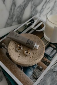 Kaboompics - Contemporary UGC Style Still Life: Hand Cream and Elegant Earrings on a Travertine Tray Over a Marble Surface