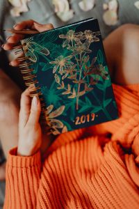 A woman in an orange sweater holds the 2019 calendar in her hands