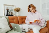 Woman uses laptop - working from home - reading a book