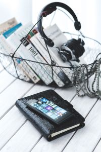 Black smartphone and headphones and a basket of books