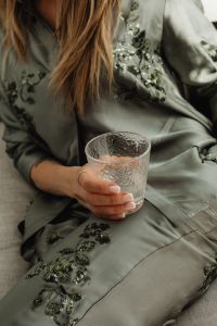 Woman in Satin Ensemble with French Manicure Holding a Glass of Water