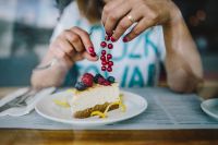Woman Enjoying Cheese Cake and a Coffee with Fruits in a Cafeteria