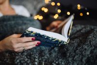 Kaboompics - Young woman at home reading Hygge book and drinking