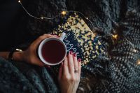 Kaboompics - Young woman at home reading Hygge book and drinking tea