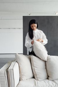 Kaboompics - Young Asian woman improves cushions on linen couch