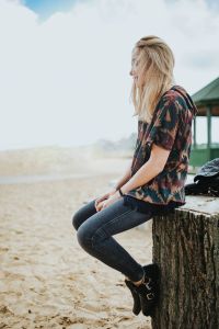 Kaboompics - Beautiful blonde woman relaxing with a can of coke on a tree stump by the beach