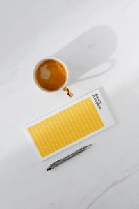 Top view of a marble desk with coffee, notebooks and pen