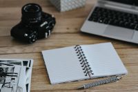 Black-and-white photos with a silver laptop, a notebook and a camera