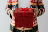 Close up of man wearing a Christmas suit and hand holding red box