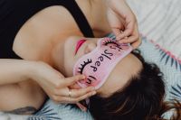 Kaboompics - Joyful girl relaxing in bedroom - top view of brunette women in pink sleeping mask