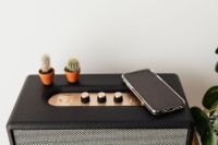 Kaboompics - Black speaker on marble table, white wall, mobile phone, cacstus