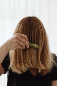 Kaboompics - A woman combs her hair with a jade comb