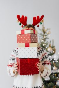 Woman with Gifts Wearing Christmas Sweater and Reindeer Horns on Head