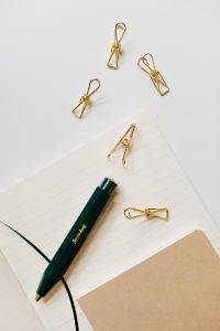 Pen, clips and notebooks on a white desk