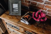 Kaboompics - Photo frame, books and pink flowers in a vase on a wooden commode