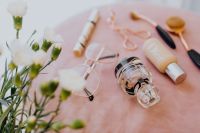 Kaboompics - Makeup brushes, eyelash curler & a bottle of perfume on pink velvet