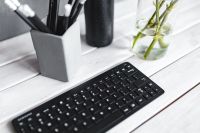 Black keyboard with pencils on a white table