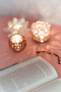 Kaboompics - An open book, candles and glasses on a pink background