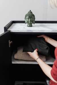 Woman putting clothes on shelf