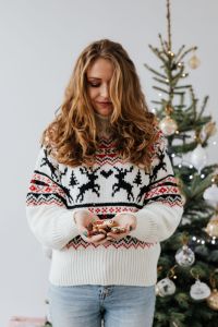 The woman in the Christmas sweater holds gingerbread