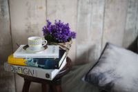 Kaboompics - Books, purple flowers and a white cup on a wooden stool by the bed