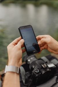 The photographer is using his phone at the lake