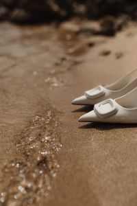Kaboompics - White high-heeled open-back pumps with front embellishment - Pointed toe - Ankle strap with elastic insert
