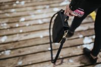 Woman with a black bag and a can of coke walking on a wooden pier