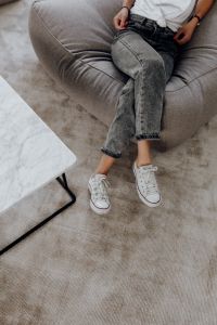 Woman wearing grey jeans & white trainers