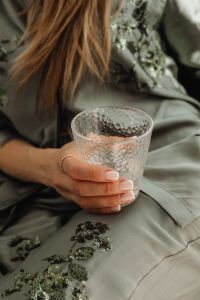 Woman in Satin Ensemble with French Manicure Holding a Glass of Water