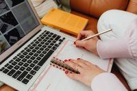 Woman uses laptop - working from home - writing in the planner