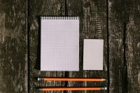 White notepad with pencils on a wooden background