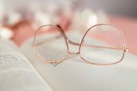 Kaboompics - An open book, glasses and a cotton branch on a pink background