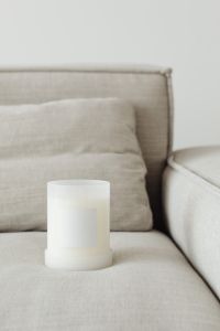 Kaboompics - Candle in white glass with label on linen couch