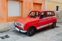 An old red Renault 4 car parked on the street in Izola, Slovenia